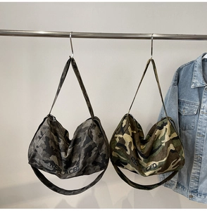 Détail de sacs hobo en toile camouflage avec texte REPLACED et bandoulière large