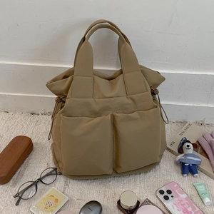 Detail shot of khaki nylon tote bag with front pockets and lifestyle accessories