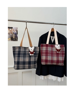 Detail of navy and burgundy plaid tweed tote bags featuring cute plush puppy charms