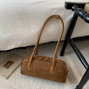 Detailed view of brown suede baguette bag with contrast stitching and double zippers
