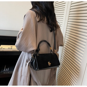 Detailed side view of black vintage handbag with gold clasp and twisted handle in home setting