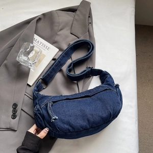 Détail d'un sac demi-lune en denim bleu marine avec une large bandoulière ajustable
