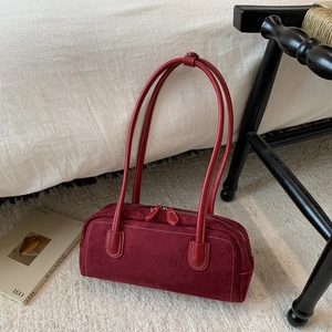 Detail of burgundy suede pillow bag featuring white contrast stitching and double top handles