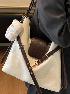 Chic cream and brown leather tote bag with plush charm and adjustable shoulder strap