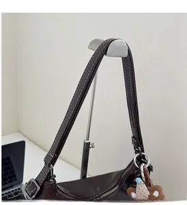 Detail view of brown faux leather shoulder bag with white stitching and plush bear charm