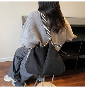 Black suede hobo bag featuring a stylish black and white striped woven shoulder strap