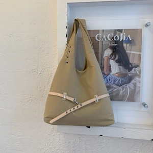 Detail of canvas tote bag showing khaki fabric texture and stylish metal eyelet straps