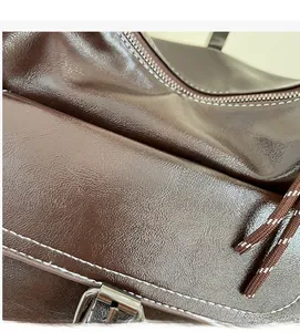 Detail of dark brown vintage oil wax leather texture with white stitching and silver buckle