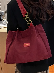 Burgundy faux suede tote bag with gold chain strap detail shown on shoulder