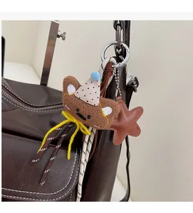 Detail of creative plush bear charm with party hat and star tag on dark leather bag