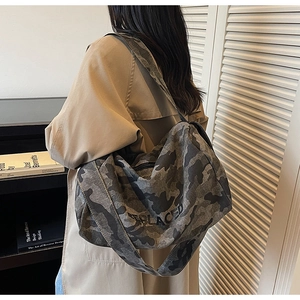 Détail du sac fourre-tout en toile camouflage gris avec texte gravé et large bandoulière