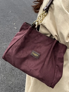 Stylish deep purple suede tote bag with brown leather handles and gold chain strap detail