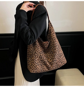 Fashionable leopard print tote bag with brown leather straps worn on shoulder by model