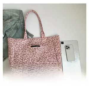 Comparaison de taille du cabas léopard rose avec un iPad et une veste en jean
