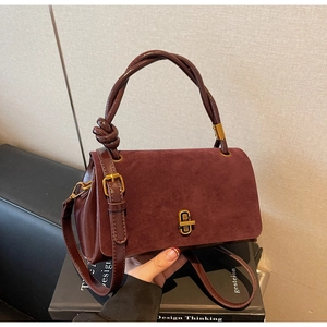 Detail of burgundy suede leather handbag with knotted handle and vintage gold metal lock