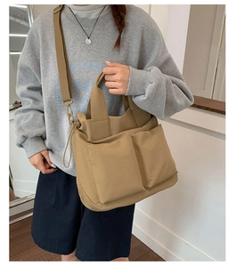 Detail of khaki nylon tote bag with large front pockets and adjustable shoulder strap
