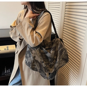 Détail du sac en toile camouflage avec lettrage PLACED et large bandoulière noire