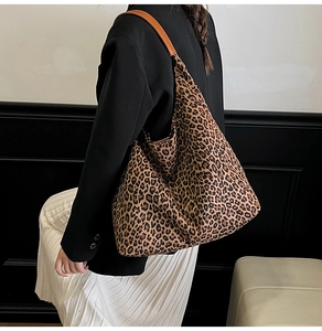 Detailed side view of large leopard print tote bag with brown leather shoulder straps