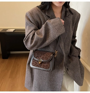 Dettaglio borsa a tracolla leopardata con chiusura a U dorata su un blazer di tweed