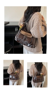 Detail of dark brown leather backpack featuring silver buckle and cute plush bear charm