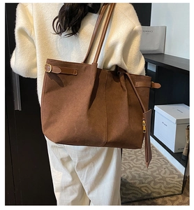 Detail of a brown suede tote bag with long shoulder strap and matching zipper pouch