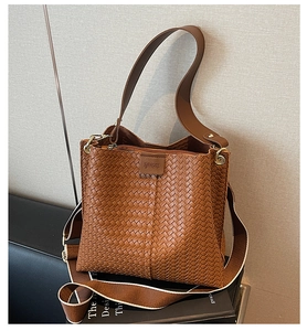 Détail d'un sac seau tressé marron avec texture en cuir et patch logo de marque