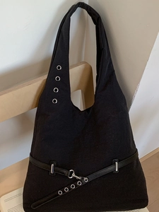 Minimalist black canvas tote bag with silver eyelets and metal hardware on wooden chair