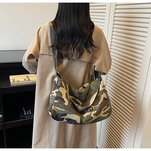 Détail du sac bandoulière en toile camouflage avec large bandoulière et imprimé de lettres