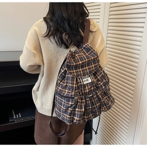 Detail of vintage blue and brown checkered backpack featuring drawstring flap and side pockets
