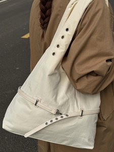 Minimalist beige hobo tote bag with silver eyelets and large capacity shown on model