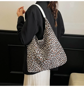 Rear view of model carrying a large leopard print tote bag with white shoulder straps