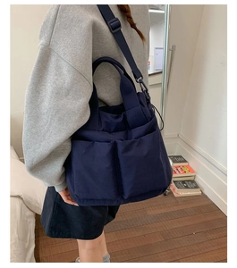 Navy blue nylon tote bag detail with large utility pockets and adjustable strap for daily use