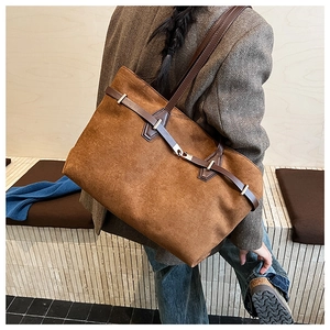 Détail d'un grand sac fourre-tout en daim marron avec des lanières en cuir sur un mannequin