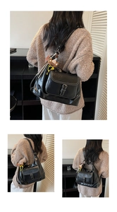 Detail of black PU leather backpack featuring metal buckle and bear charm decoration