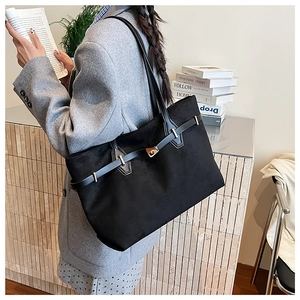 Gros plan d'un grand sac cabas en daim noir avec fermoir doré et fines bandoulières