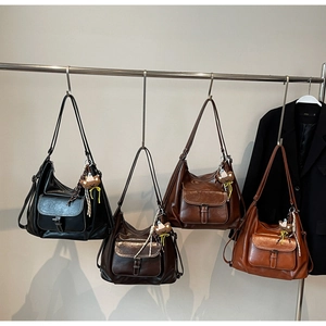 Detail of four hobo shoulder bags in black and brown with cute bear charms on metal rack