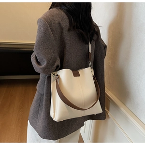Vue détaillée du sac seau bicolore crème et marron avec large bandoulière sur modèle