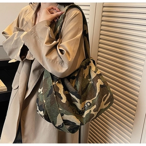 Détail d'un grand sac cabas en toile camouflage avec lettrage PLACED sur un trench-coat kaki