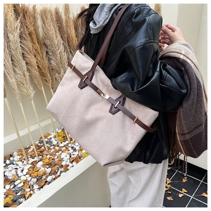 Détail d'un grand sac cabas beige avec lanières en cuir marron et boucle dorée en automne