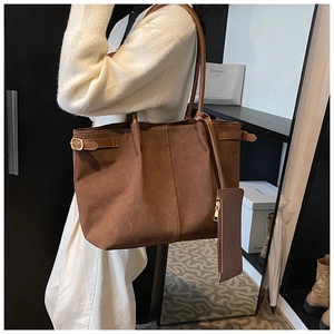 Close-up of brown suede tote bag featuring side metal buckle and a small matching pouch