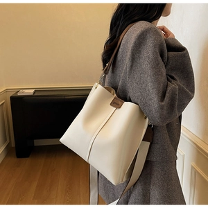 Détail du sac cabas en cuir crème avec empiècement logo marron et large bandoulière