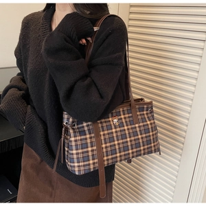 Detail of checkered tote bag featuring cartoon embroidery and dark leather shoulder straps