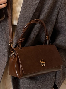 Chic brown patchwork handbag with gold clasp and twist handle on grey blazer