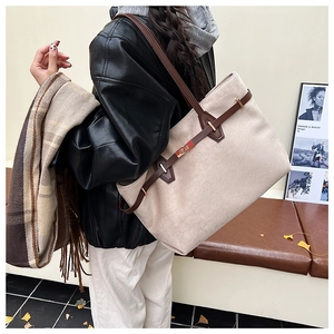 Détail d'un sac cabas en toile avec lanières en cuir marron et boucle dorée pour le travail