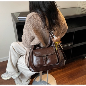 Detail of vintage coffee brown shoulder bag with cute bear pendant on high-gloss PU leather