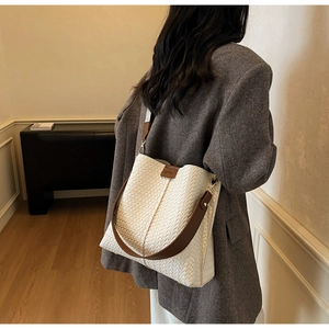 Gros plan du sac cabas blanc tissé avec poignées en cuir marron et étiquette de marque