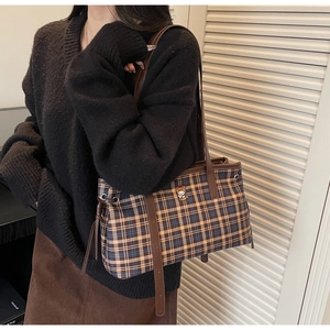 Detail of checkered tote bag with cartoon bear patch and brown faux leather handle