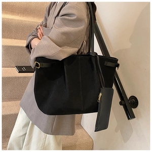 Detail view of black suede tote bag showing the side gold buckle and matching pouch