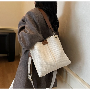 Vue latérale détaillée d'un sac seau blanc tressé avec bandoulière en cuir marron et tissu