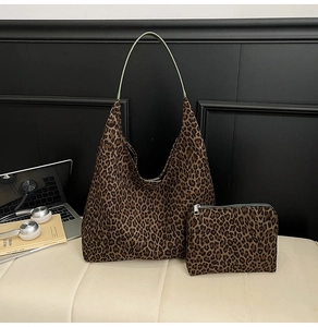 Detailed set of leopard print tote and matching pouch on a cream leather bench